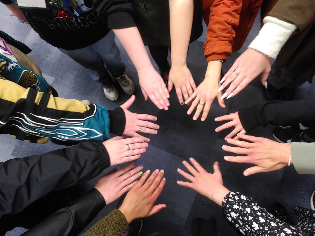 A group of people in a circle with their hands in the middle.